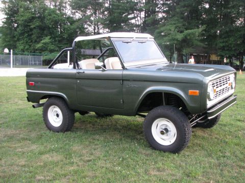 1979 Ford Bronco - This 1979 Ford Bronco features a dark green exterior, white wheels, and a removable white soft top, offering a classic off-road look.