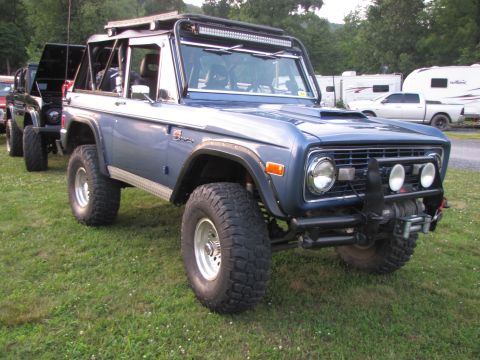 1979 Ford Bronco - Modified blue Ford Bronco parked on grass with other vehicles in the background.