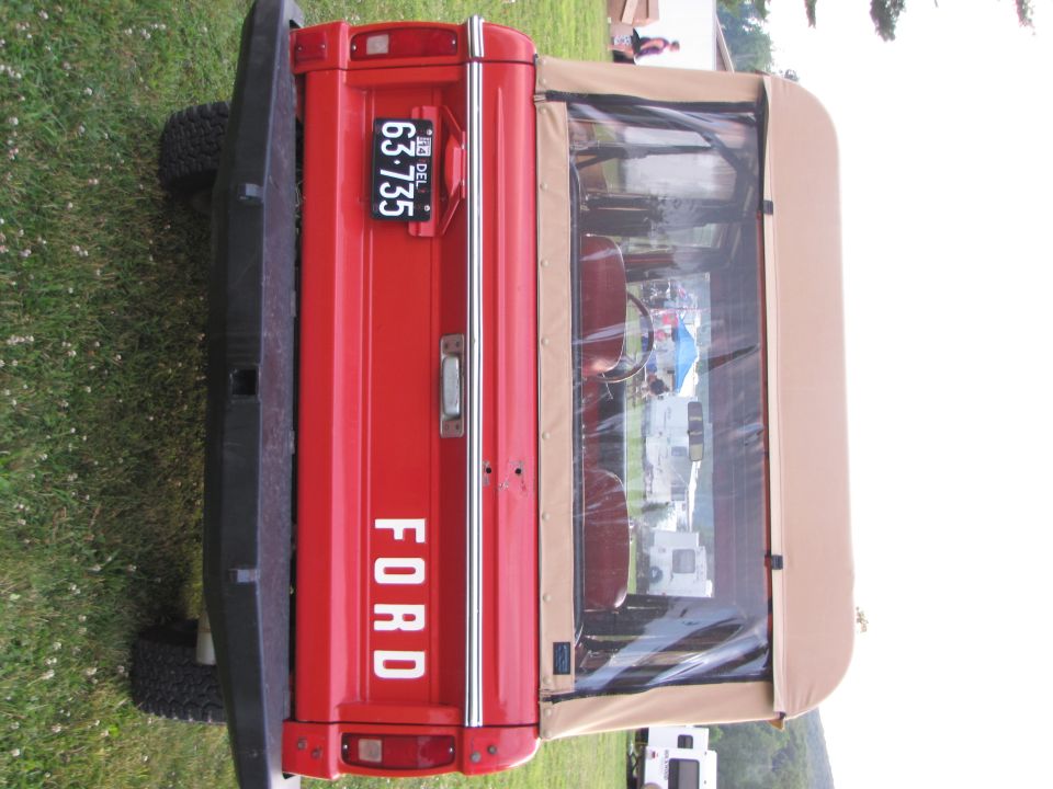 Red 1978 Ford Bronco rear view with a tan soft top and license plate 63-735