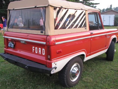 1979 Ford Bronco - Rear view of a red and white 1979 Ford Bronco, a tan soft top and chrome accents.