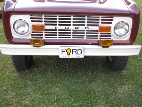 1979 Ford Bronco - Front view of a maroon and white vehicle, a large grille and a custom 'FORD' license plate.