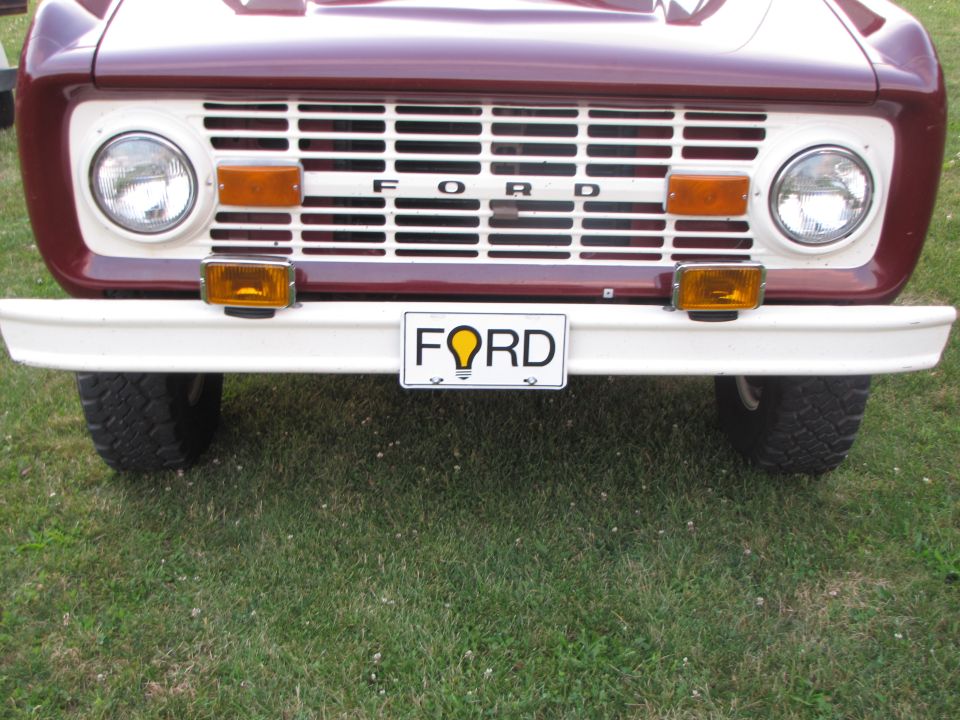 Maroon and white vehicle front with prominent grille and 'FORD' license plate