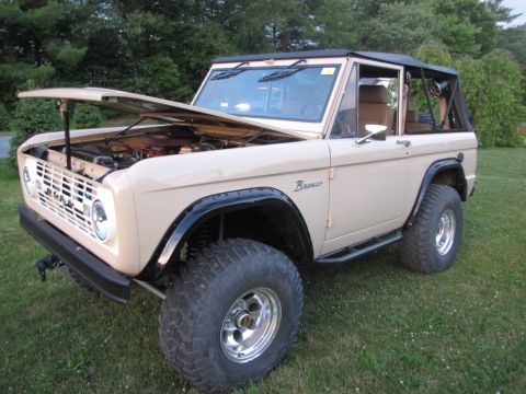 1979 Ford Bronco - This tan Ford Bronco, likely a 1978 model, is shown with its hood up, revealing the engine compartment.