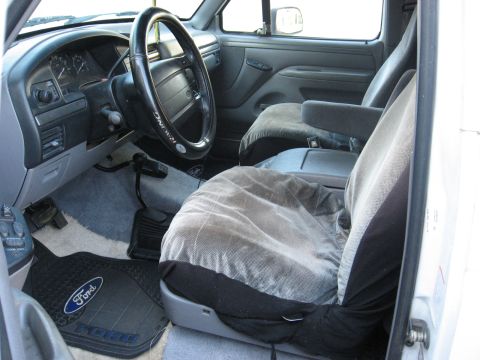 1994 Ford Bronco - The interior of a 1992 Ford truck, a dashboard, steering wheel, and cloth seat covers.