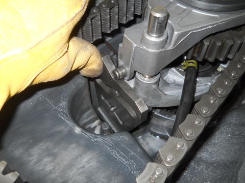 1992 Ford Bronco - Close-up of engine timing chain and gears being adjusted by a gloved hand.