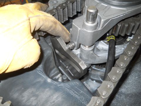 1992 Ford Bronco - Close-up view of an engine's internal components, including a timing chain and gears, being worked on by a gloved hand.