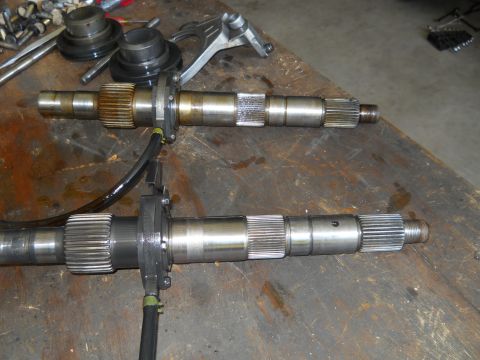1992 Ford Bronco - Two metal shafts with splines and flanges are laid out on a workbench, possibly for repair or replacement.