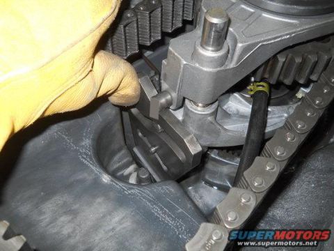 1994 Ford Bronco - A gloved hand adjusts the engine timing chain and gears, with a "Supermotors.net" watermark visible.