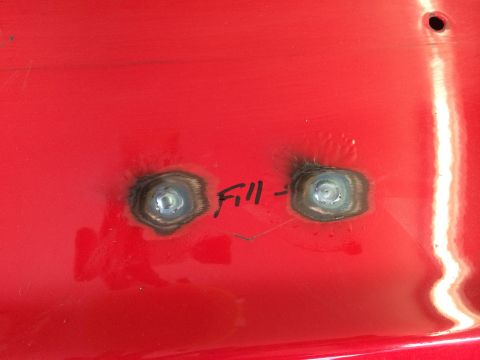 1964 Ford Fairlane - Close-up of a red metal surface showing two welded bolts and handwritten text indicating a fill operation.