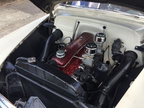 1964 Ford Fairlane - The engine bay of a classic car is shown, a V8 engine with chrome air cleaners.
