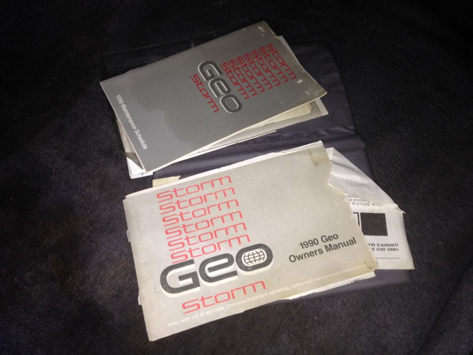 Two Geo Storm owner's manuals, one dated 1990, stacked on a dark surface