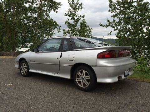 1990 Geo Storm GSi - A silver 1990 Geo Storm GSi is parked outdoors near a body of water.