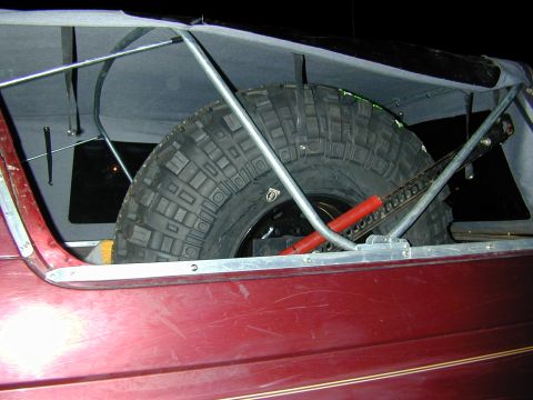 1996 Ford Bronco - A spare tire and jack are stored in the rear of a vehicle, under a canvas cover.