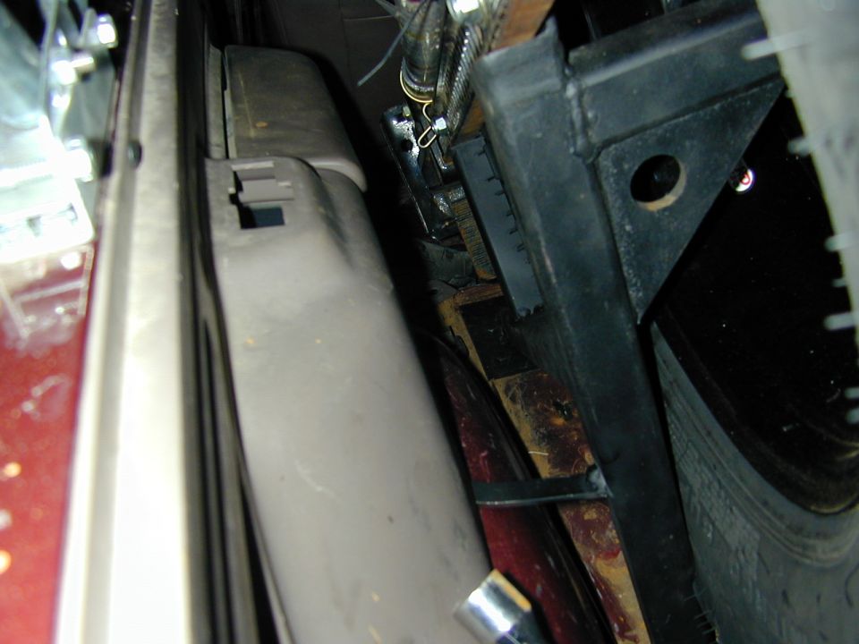 Close-up gap between gray plastic vent panel and black metal bracket with wiring