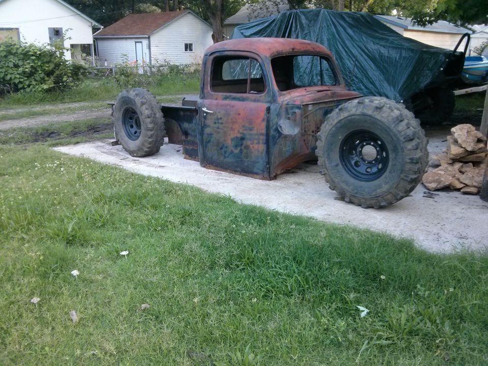 Old pickup truck body, missing fenders and hood, on large off-road tires