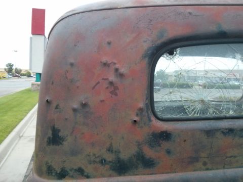 1986 Ford Bronco - This heavily rusted truck body shows significant damage, including bullet holes and a broken rear window.
