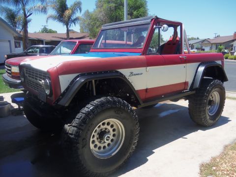 1968 Ford Bronco - A modified Ford Bronco with a custom paint job sits in a driveway next to another vehicle.