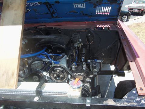 1968 Ford Bronco - The engine bay of a vehicle, showing various mechanical components and blue hoses. Text is visible on an interior panel.