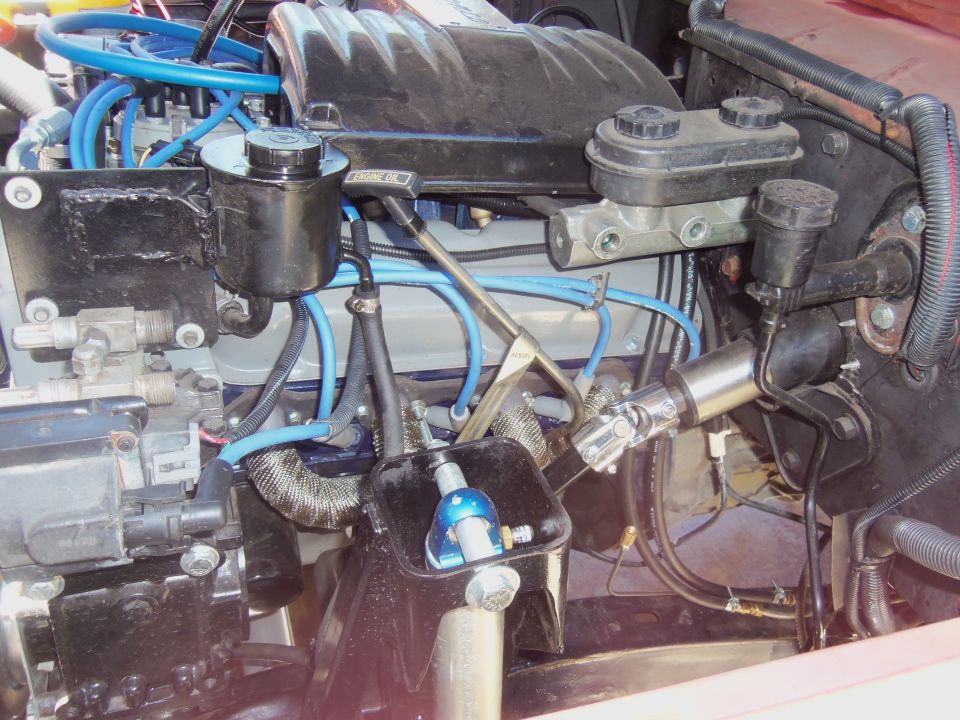 Engine bay detail showing brake master cylinder, power steering reservoir, and various hoses and wiring