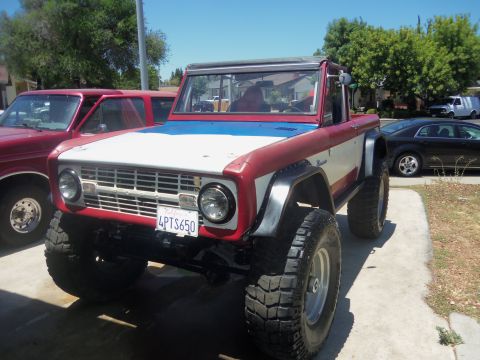 1968 Ford Bronco - A red, white, and blue Ford Bronco is parked next to another vehicle.
