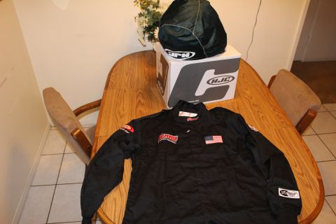 2003 Ford Crown Victoria - black racing jacket with a USA flag patch lies on a wooden table beside a helmet in a bag resting on an HJC box.