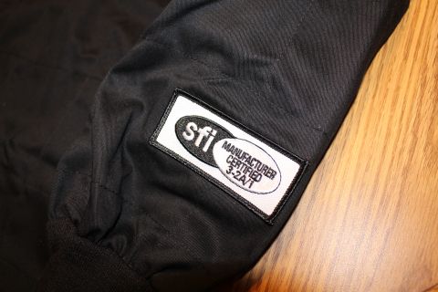 2003 Ford Crown Victoria - Close-up of an SFI 3.2A/1 manufacturer-certified patch sewn onto the sleeve of a black racing jacket.