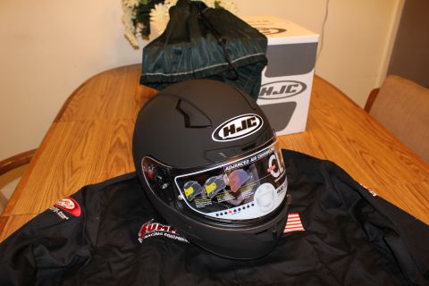 2003 Ford Crown Victoria - matte black HJC full-face helmet sits on a black racing jacket with the helmet's HJC box visible in the background.