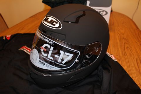 2003 Ford Crown Victoria - matte black HJC CL-17 full-face helmet with its visor spec sticker still attached, resting on a wooden surface.