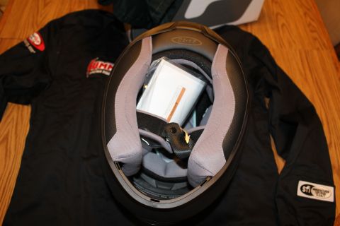 2003 Ford Crown Victoria - Looking into the open interior of a helmet revealing the gray padded liner and printed paperwork tucked inside, on a black jacket.