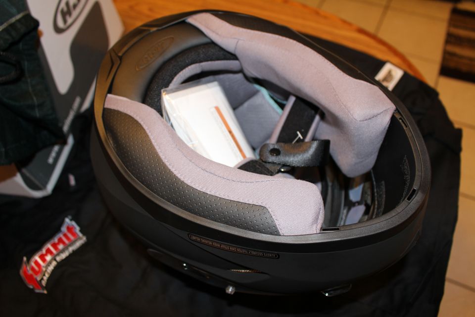 Inside view of helmet showing gray cheek pads and paperwork, helmet box nearby