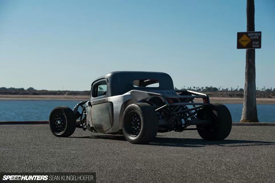Custom hot rod with exposed frame and large rear tires, viewed from the rear