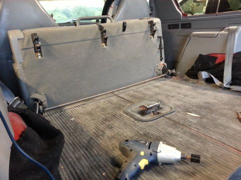 1995 Ford Bronco - The interior of a vehicle's cargo area shows a folded rear seat and a power drill on the floor.