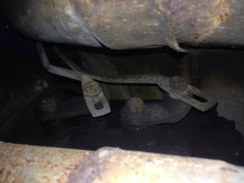 1973 Ford Torino - Undercarriage view showing rusty metal parts and fuel tank straps.