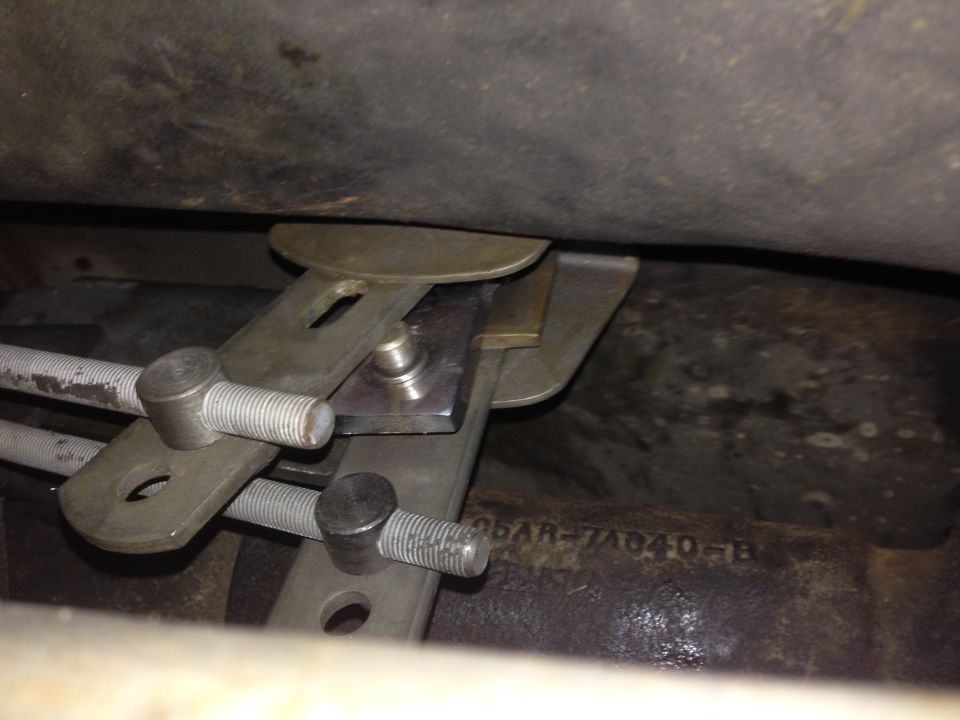 Close-up of metal linkage parts and threaded rods under a vehicle, with part number C6AR-7A040-B visible