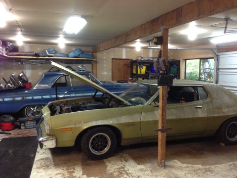 1973 Ford Torino - A green 1973 Ford Torino sits in a garage with its hood open, next to a blue classic car.