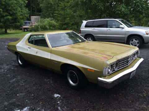 1973 Ford Torino - A vintage Ford Torino is parked outdoors next to a modern SUV, with trees in the background.