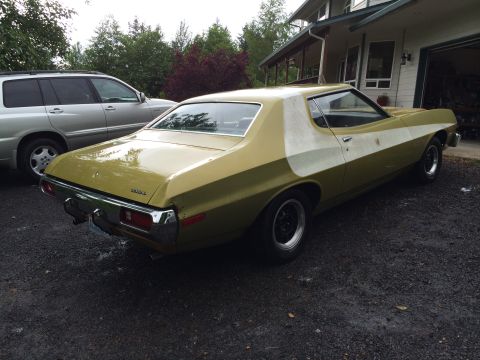 1973 Ford Torino - A two-tone 1973 Ford Torino coupe is parked next to a silver SUV in front of a house.