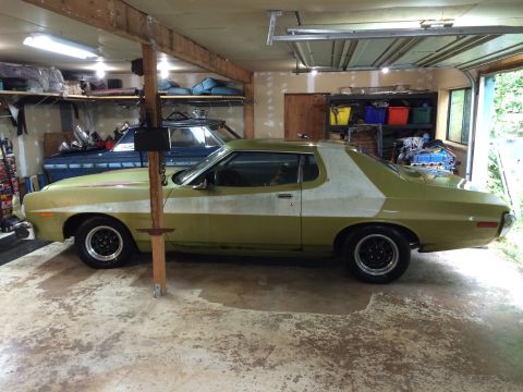 1973 Ford Torino - Side view of a 1973 Ford Torino coupe with primer on the rear quarter panel, parked in a garage.