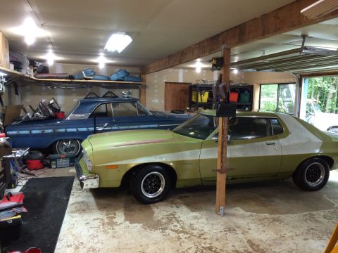 1973 Ford Torino - A green 1973 Ford Torino and a blue classic car are parked side-by-side in a cluttered garage.
