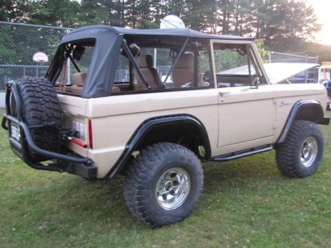 1979 Ford Bronco - 1979 Ford Bronco with a tan exterior and black soft top is parked on grass.