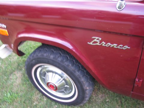 1979 Ford Bronco - The side view of a red 1979 Ford Bronco highlights its classic fender design and the iconic 'Bronco' badging.