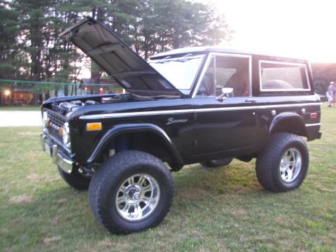 1979 Ford Bronco - This black 1979 Ford Bronco features a lifted suspension and aftermarket chrome wheels, with its hood open for display.
