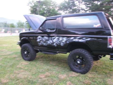 1979 Ford Bronco - This black SUV features custom skull graphics and checkered flag airbrushing, with its hood open.