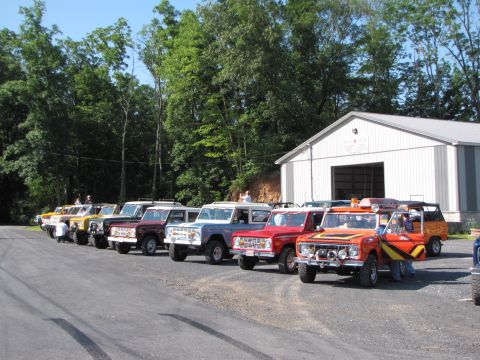 1979 Ford Bronco - A collection of Ford Broncos, likely from the 1979 model year, are lined up in front of a large building.