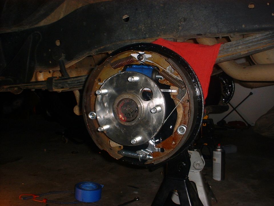 Rear drum brake assembly with new blue cylinder and red cloth, on jack stand