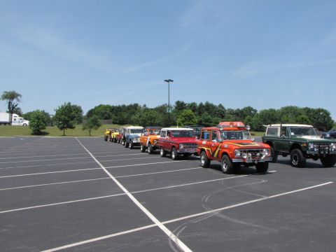 1979 Ford Bronco - Several Ford Broncos are lined up in a parking lot under a clear blue sky.