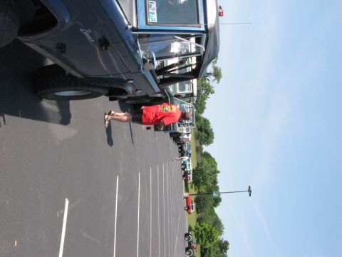 1979 Ford Bronco - A line of vehicles, including a dark blue 1979 Ford Bronco, are parked in a lot on a sunny day.