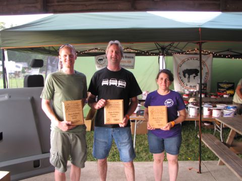 1979 Ford Bronco - Three individuals receive awards at an outdoor event, with a large panel visible to the left.
