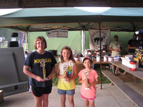 1979 Ford Bronco - Three young girls proudly display their trophies at an outdoor gathering, possibly a car show awards ceremony.