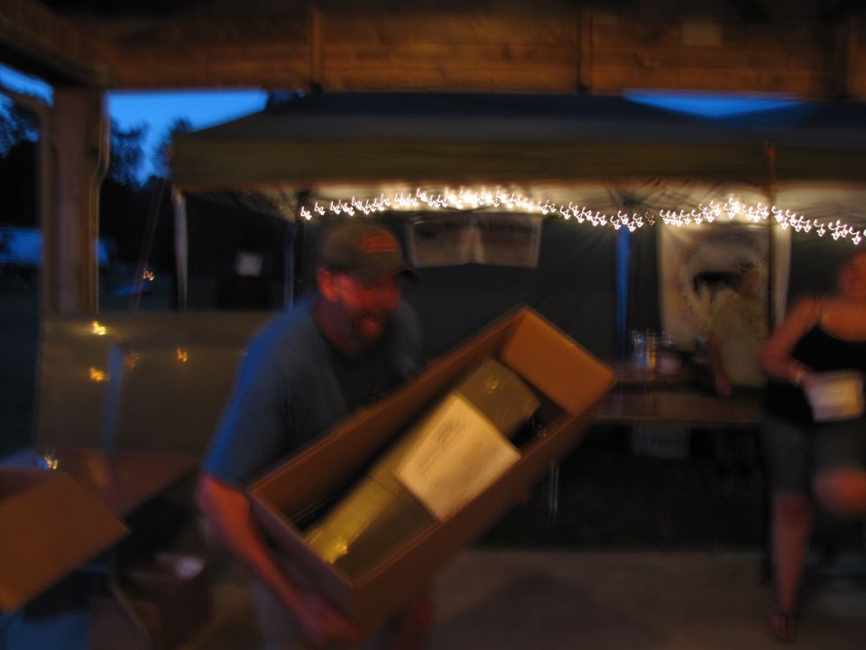 Man holding a box with a long object inside at an outdoor event